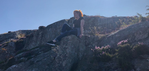 Jasmin Schwarte sitzt auf einem Felsvorsprung und genießt die Aussicht.