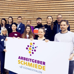 Menschen der Arbeitgeberschmiede Südwestfalen mit Logoplakat in der Hand