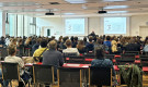 Schüler*innnen sitzen in Hörsaal und hören Vortrag zu.