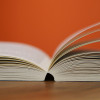 Aufgeschlagenes Buch vor orangem Hintergrund